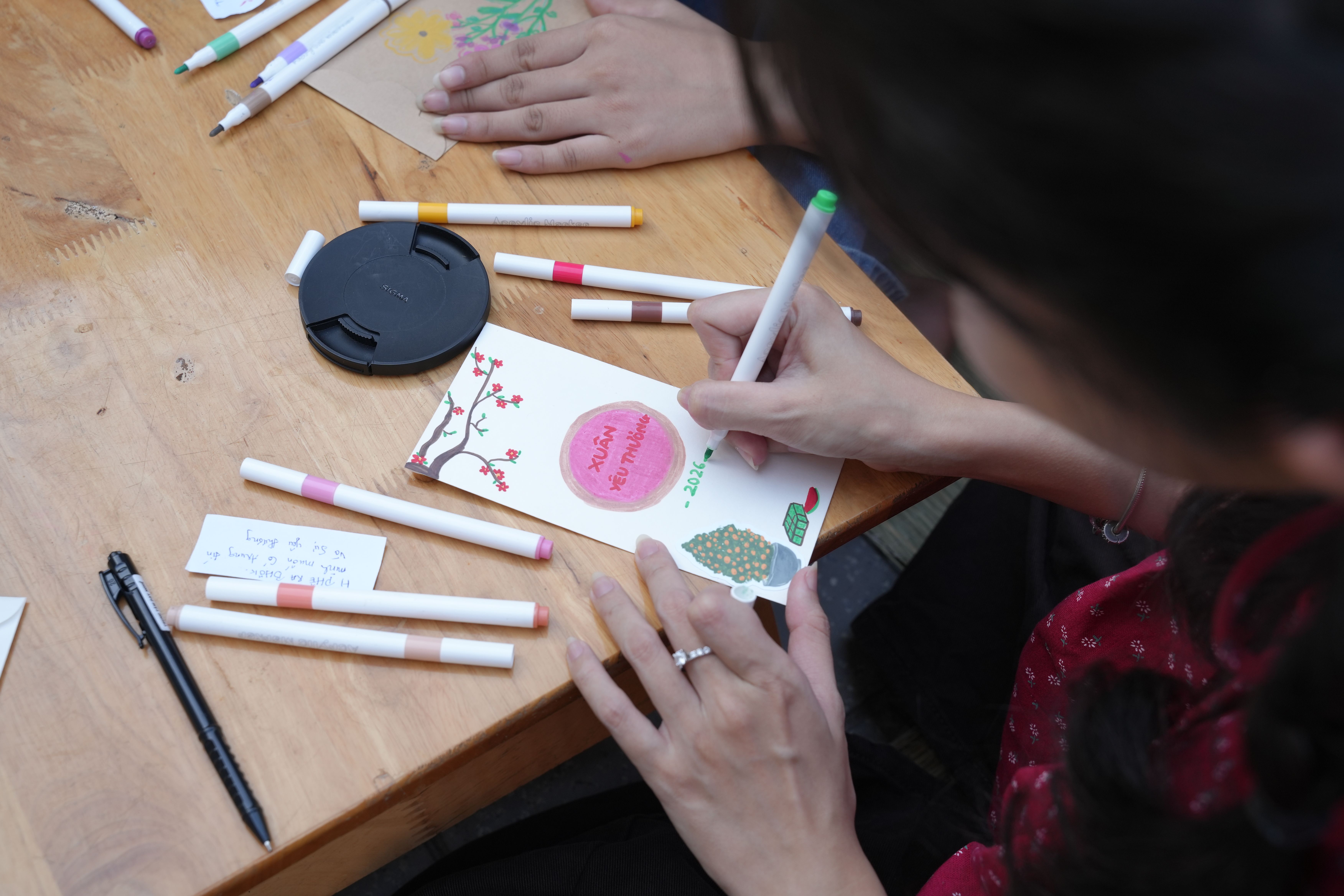 Woman designing a colorful handmade greeting card with markers at a wooden table