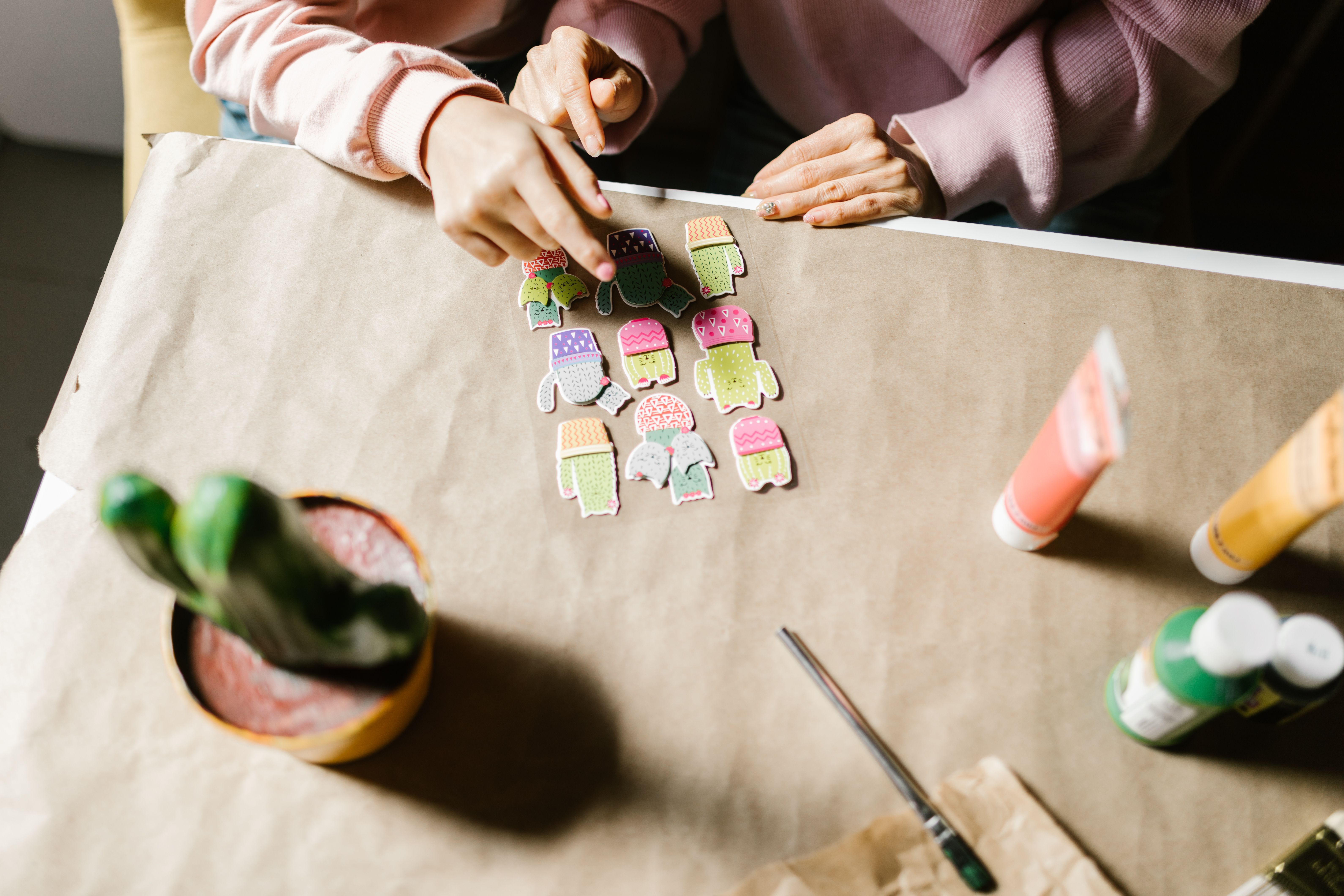 Hands arranging colorful paper cutouts for a creative handmade card design